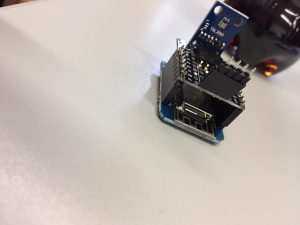 Eine elektronische Platine mit mehreren integrierten Schaltkreisen und Anschlussmöglichkeiten, die auf einem hellen Untergrund platziert ist.