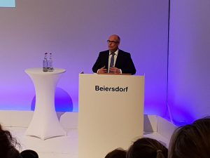Ein Mann in Anzug steht an einem Rednerpult mit der Aufschrift 