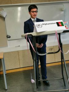 Ein junger Mann steht an einem Stehpult, auf dem ein Schild mit der Aufschrift 