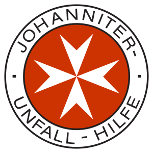 Logo der Johanniter Unfall-Hilfe: Ein roter Hintergrund mit einem weißen, achtzackigen Stern in der Mitte, umgeben von einem schwarzen Ring mit dem Schriftzug 