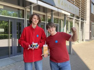 Zwei junge Menschen stehen vor einem modernen Gebäude mit der Aufschrift 