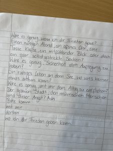 Handschriftlicher Text auf einem Notizblatt mit Fragen über das Leben, Sicherheit und zwischenmenschliche Beziehungen.
